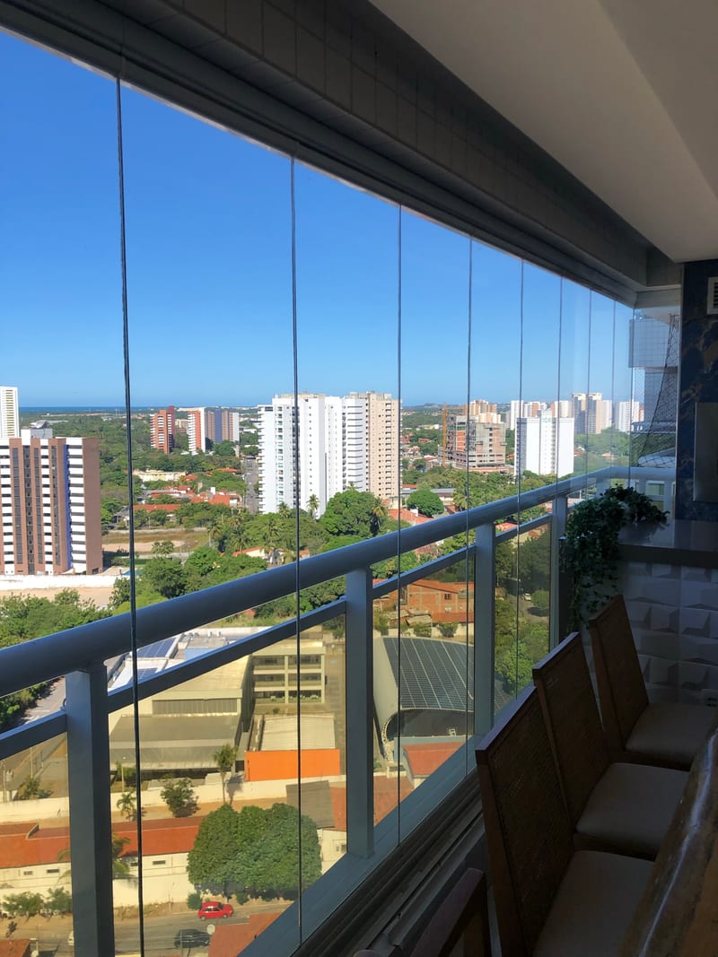 Sacada fechada com cortina de vidro de piso a teto, vista para a orla de Fortaleza