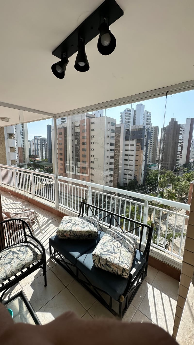 Varanda fechada com cortina de vidro, mesa posta e vista para os prédios de Fortaleza